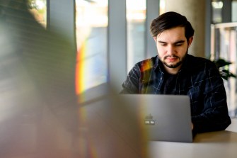 A man stares down at laptop computer screen