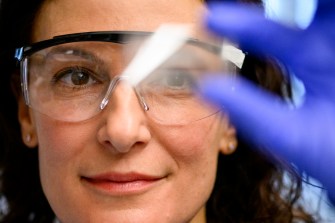 Rebecca Carrier wearing safety goggles holding up a lab sample