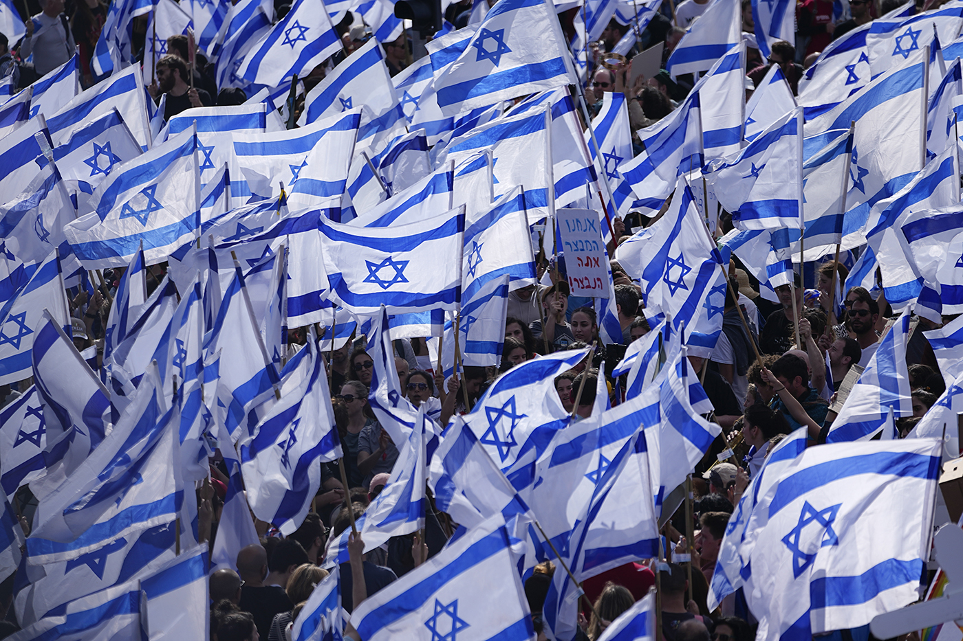 crowd of protestors waving Israeli flags