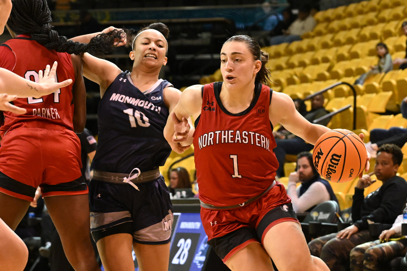 northeastern womens basketball player dribbles the ball while holding off a monmouth player