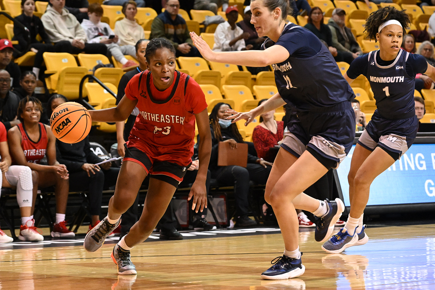 northeastern womens basketball player dribbles past monmouth player