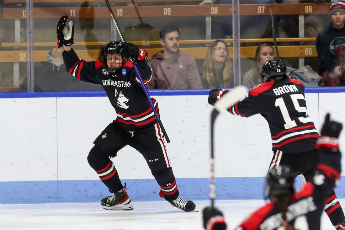 northeastern womens hockey player skating with hands up in celebration
