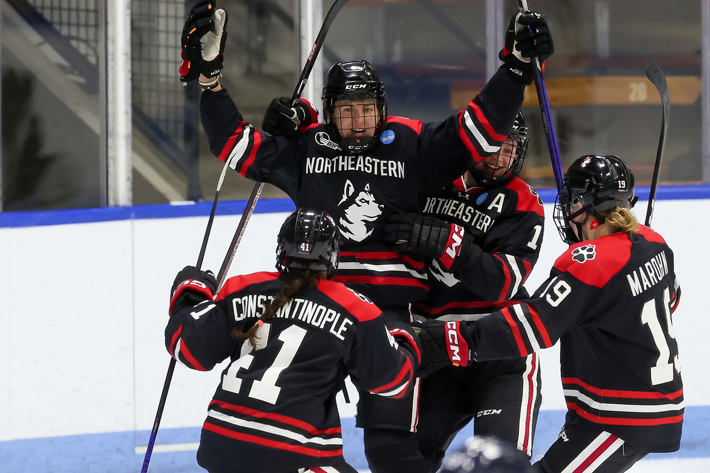 northeastern womens hockey players celebrating on the ice