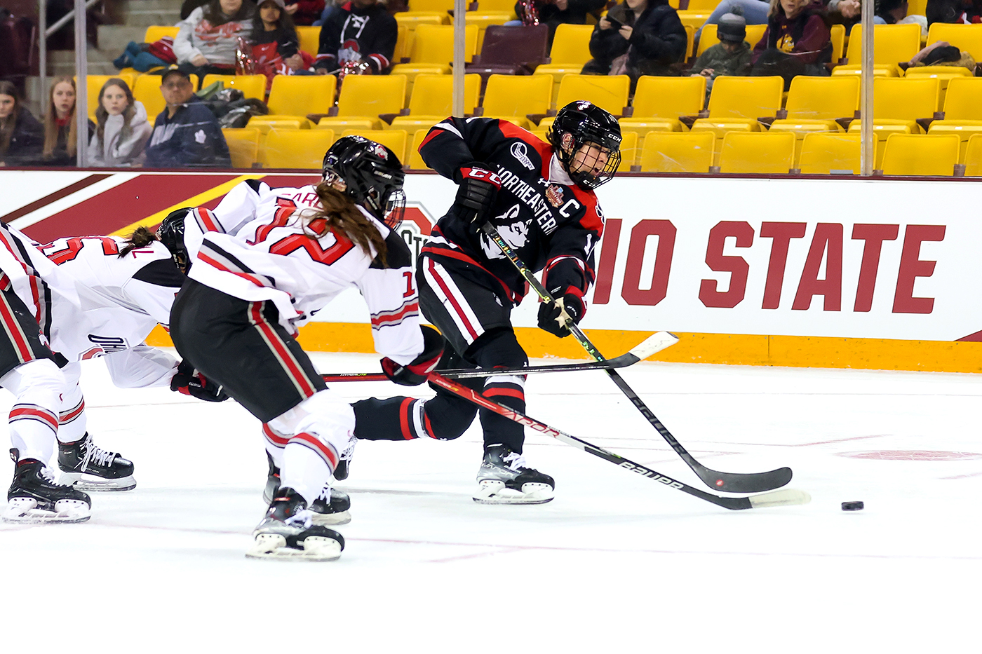 northeastern womens hockey player shooting the puck