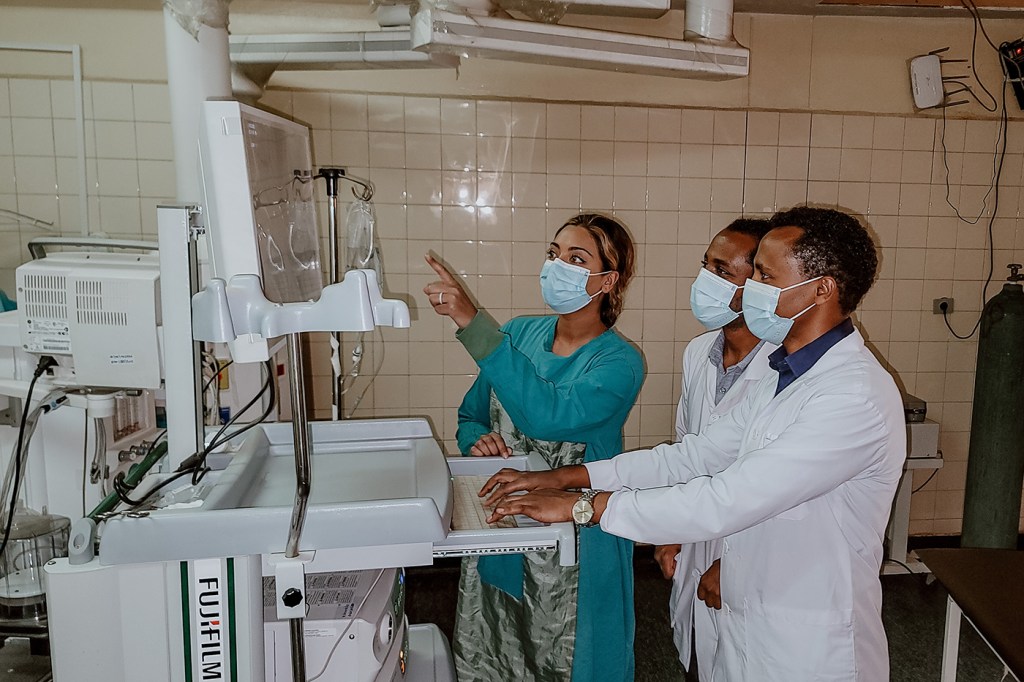 Three health care workers review medial images in a hospital lab