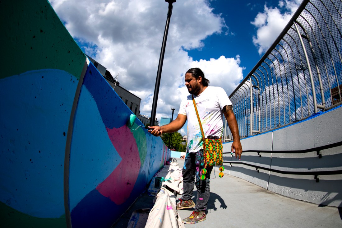 daniel anguilu painting a mural on a ramp leading into Columbus Parking Garage