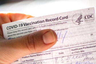 hand holding COVID-19 vaccination record card