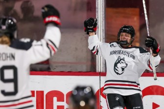 northeastern womens hockey players raise their arms in celebration