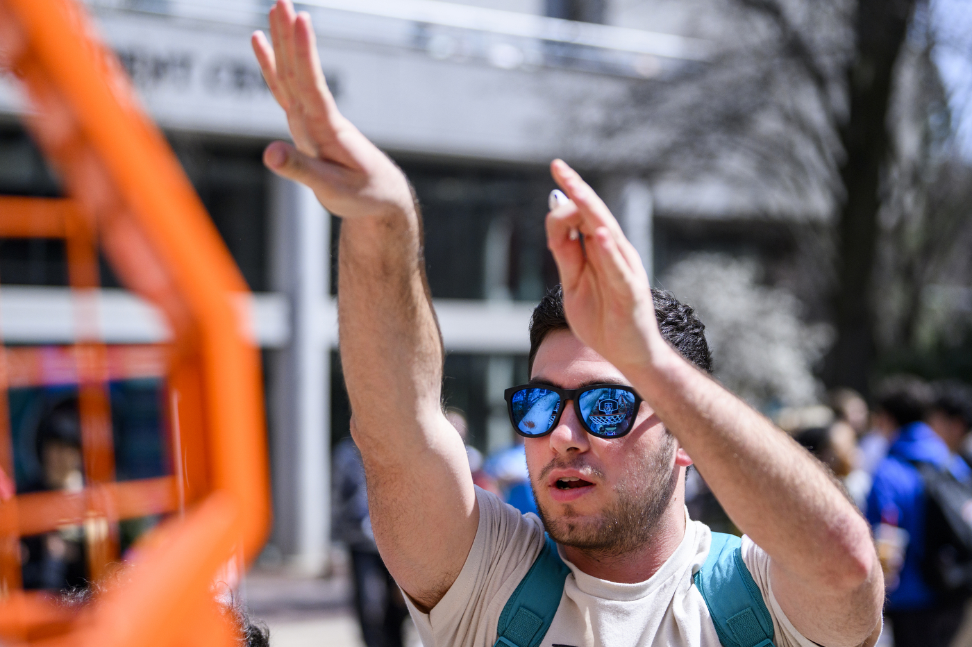 person wearing sunglasses with their hands raised in the air