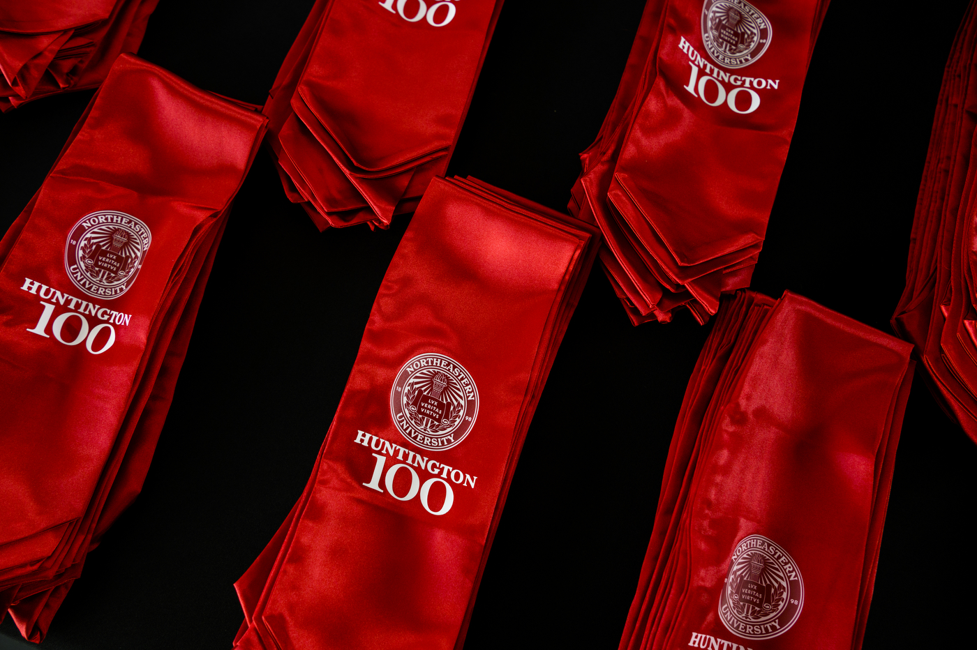 Red sashes embroidered with Huntington 100 seal are displayed on a table