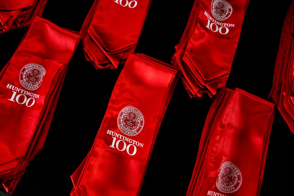 Red sashes embroidered with Huntington 100 seal are displayed on a table