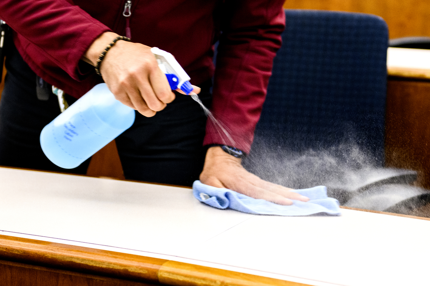 Spraying a desk with cleaner