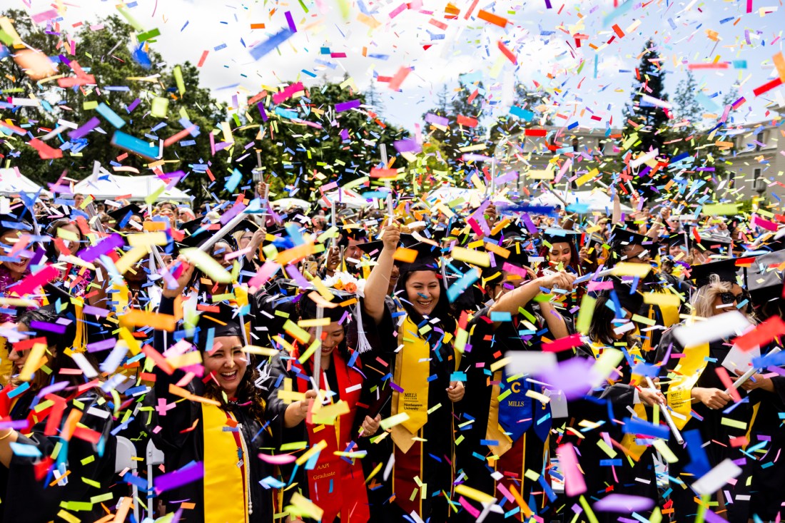Rainbow confetti falling around graduates in their caps and gowns.