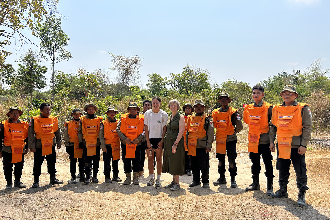 student co-op poses with Cambodian community members wearing orange vests