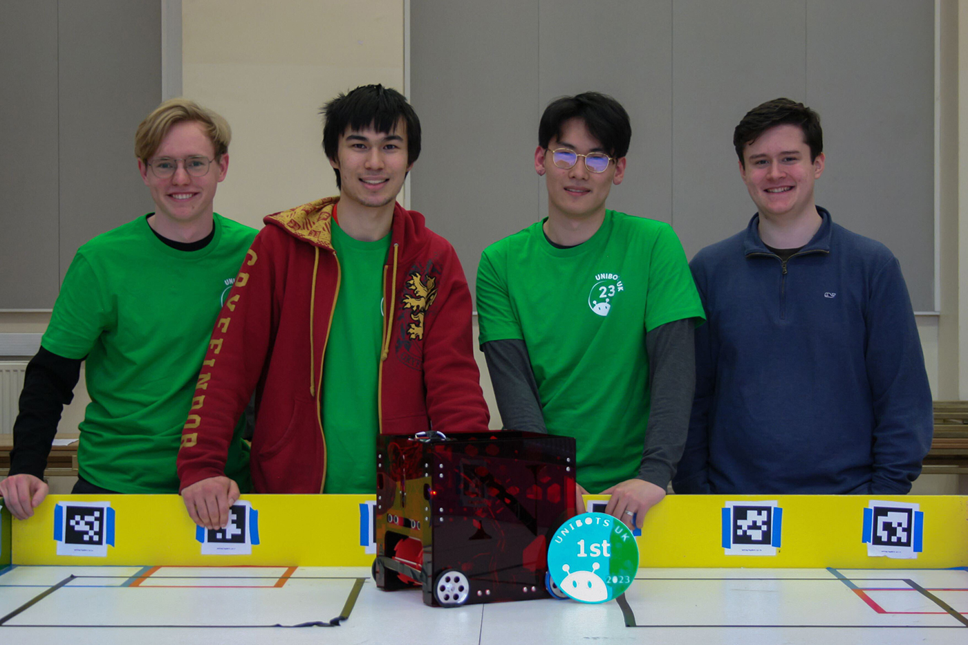 Members of Northeastern University London's robotics club stand behind their robot and a first-place placard.