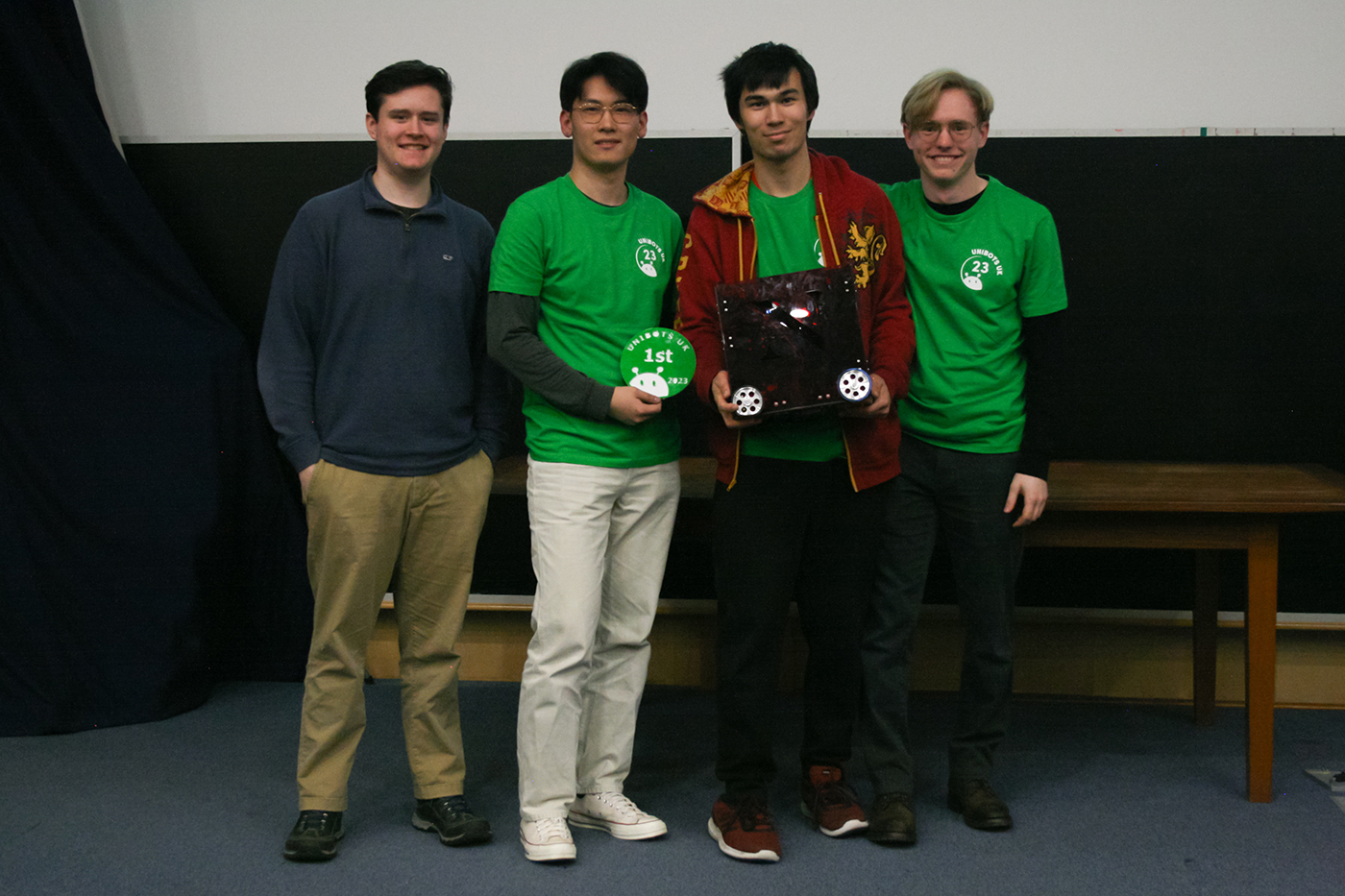 Members of the Northeastern University London robotics club hold their robot and first-place placard.