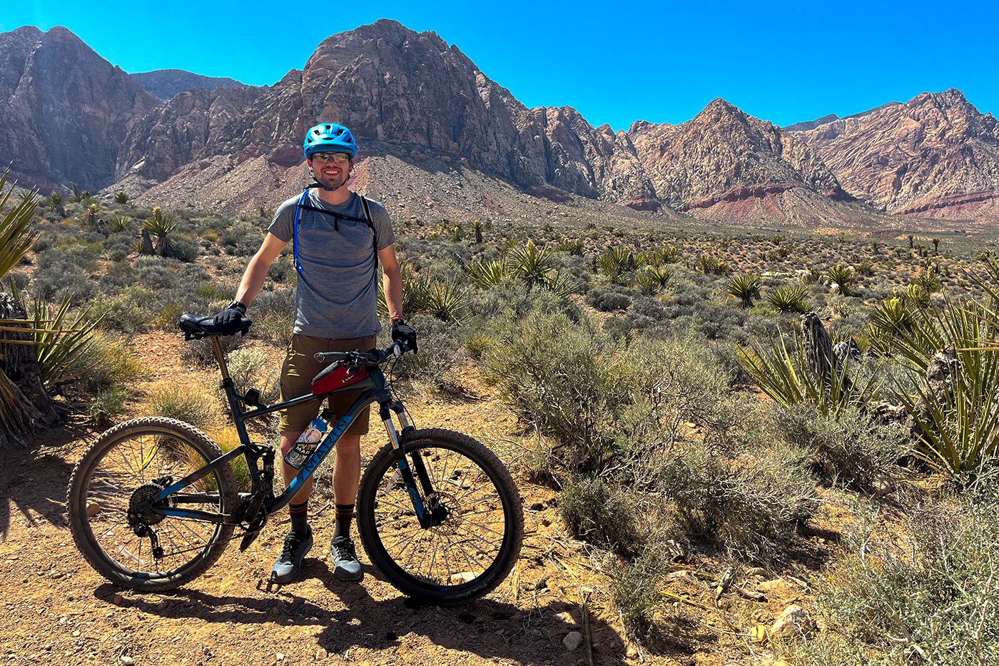 Michael Nelson stands by a bicycle with mountains in the background.