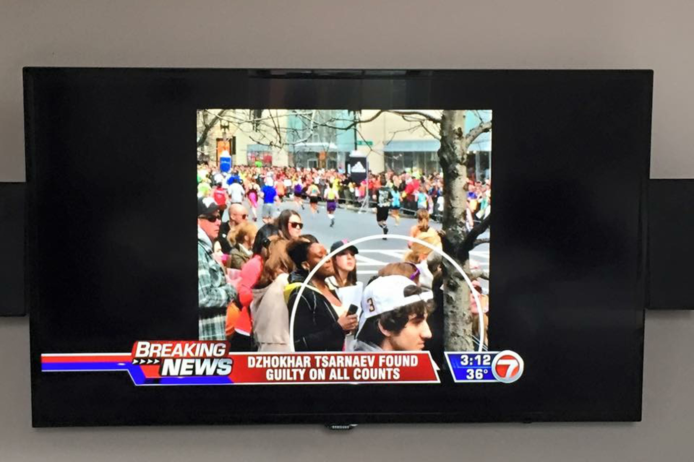 tv displaying news station image of Dzhokhar Tsarnaev standing nearby Audrey Evans