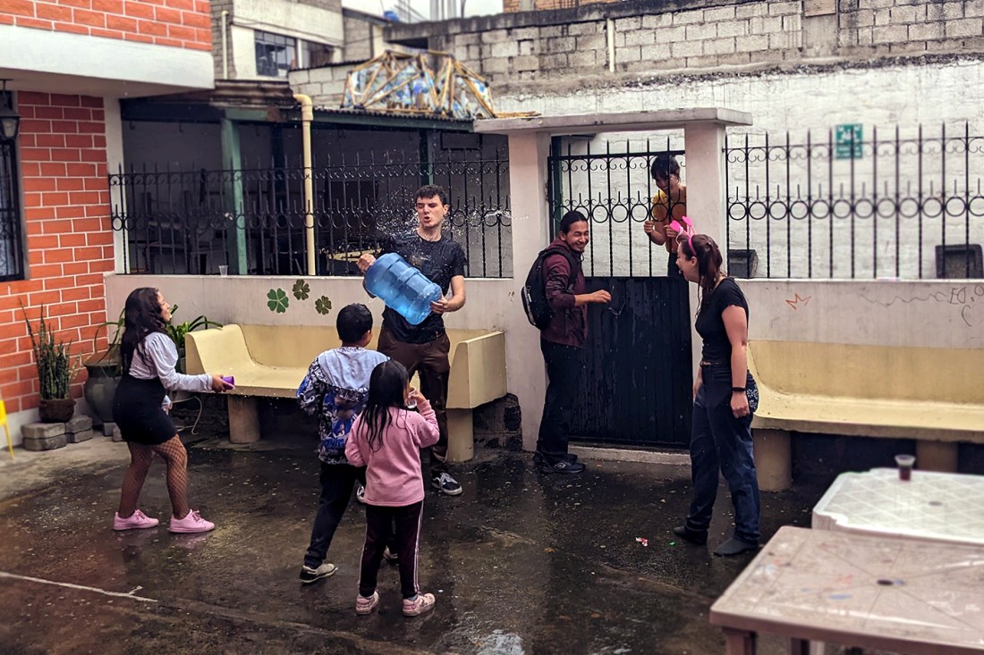 Aaron Denberg holding a jug of water in front of several Ecuadorian children