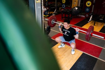 Matt Tung squatting weighted barbell