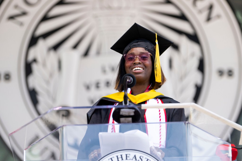 Kristine Umeh smiling in cap and gown at graduate commencement ceremony