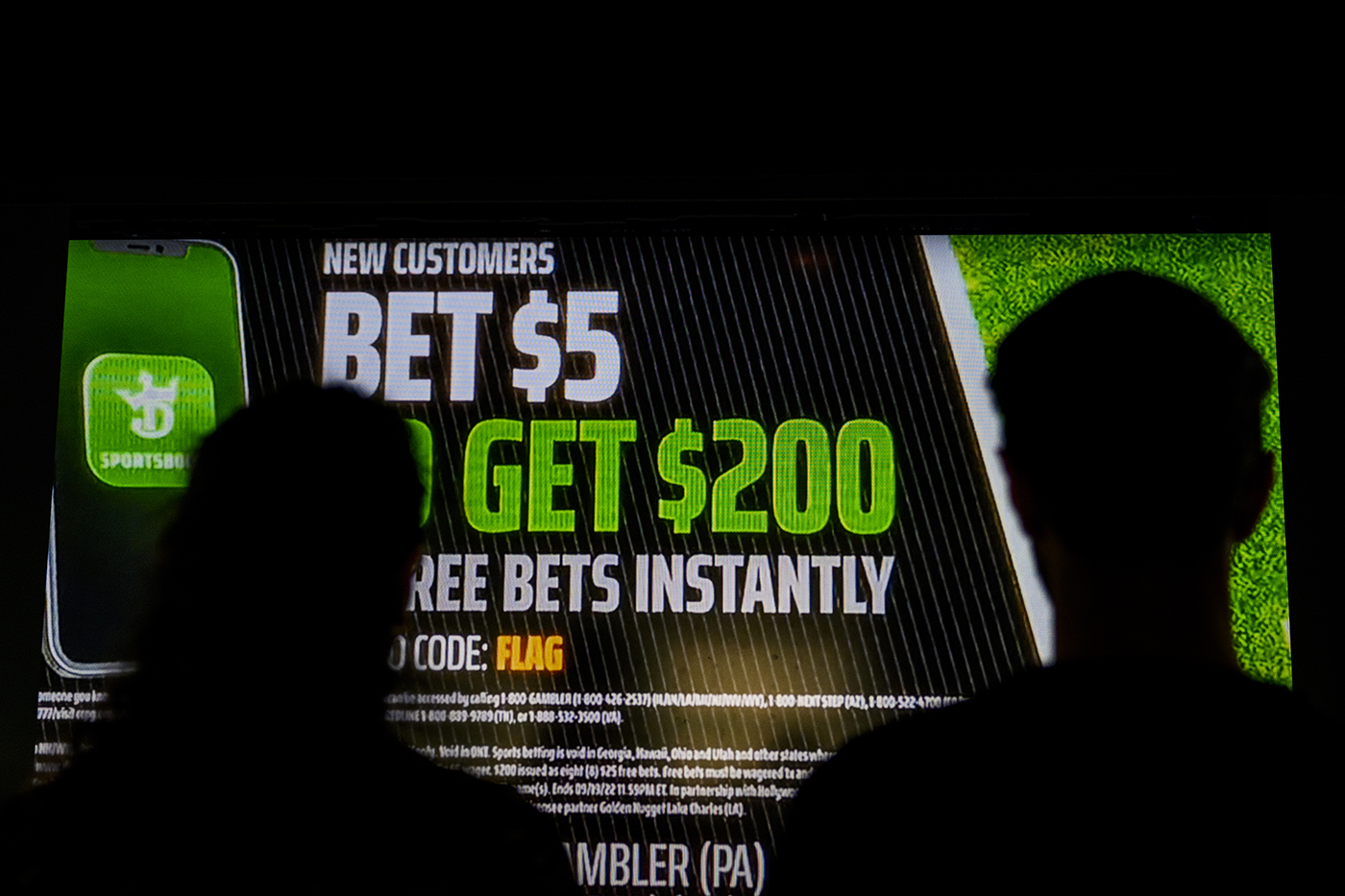 Silhouette of two people looking at a sports betting ad
