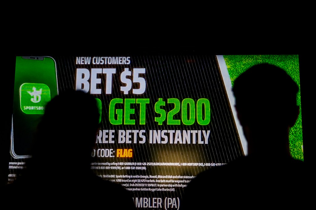 Silhouette of two people looking at a sports betting ad