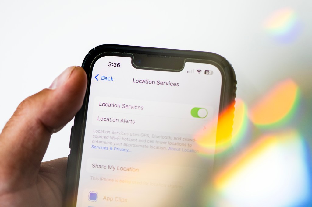 person holding iPhone with location services tracking toggle on in settings
