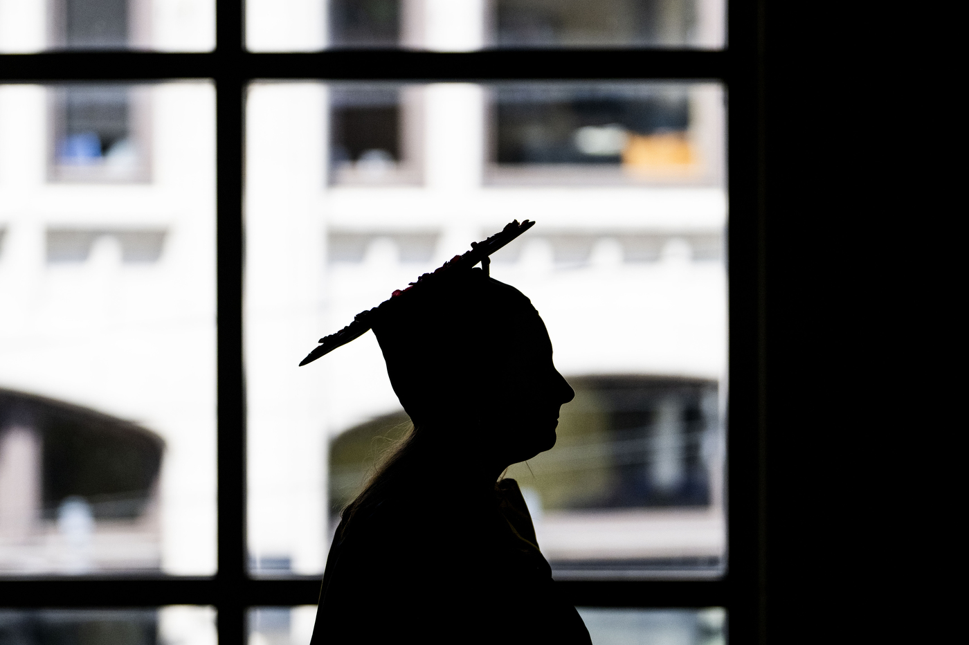 silhouette of person wearing cap and gown