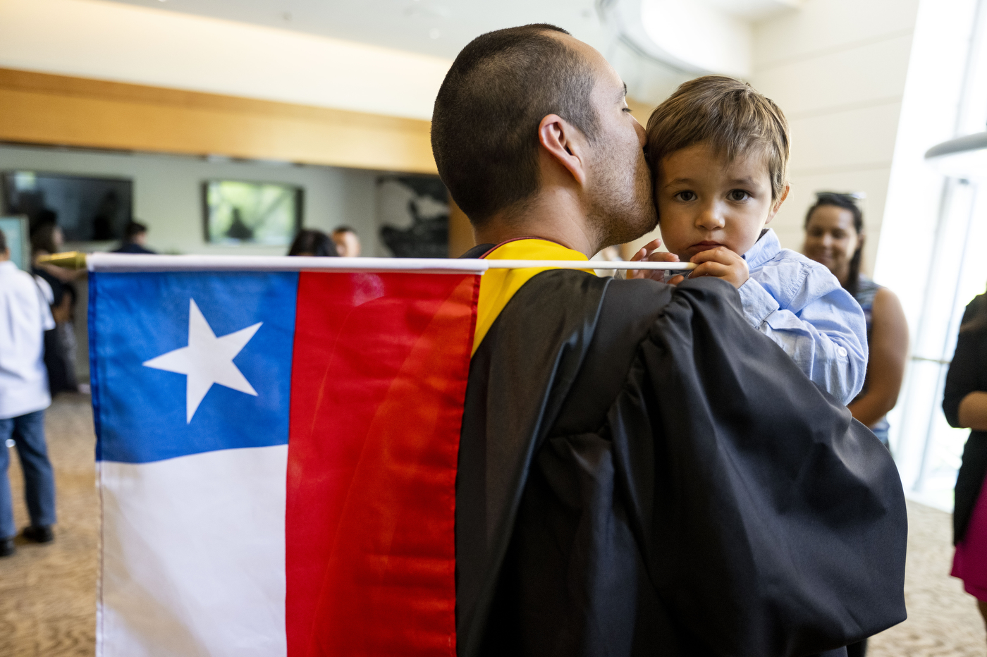 graduate holding a child carrying a Puerto Rican flag