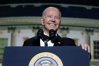 president Joe Biden smiling in front of microphone