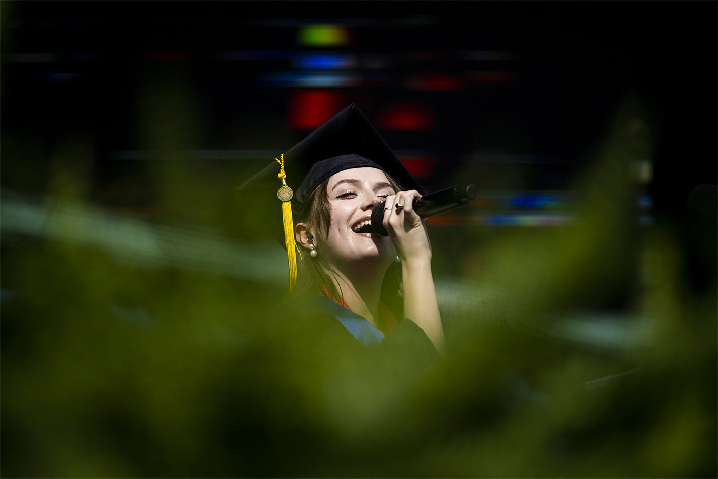 Person singing national anthem in graduation cap and gown
