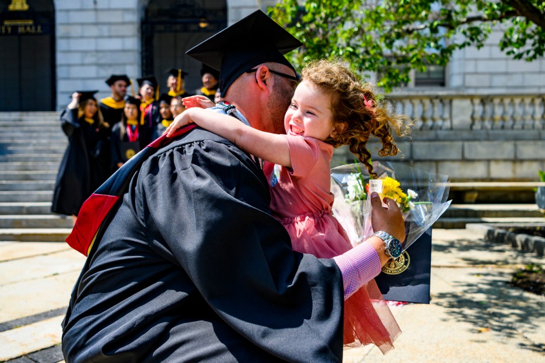 Northeastern graduate hugging a child. 