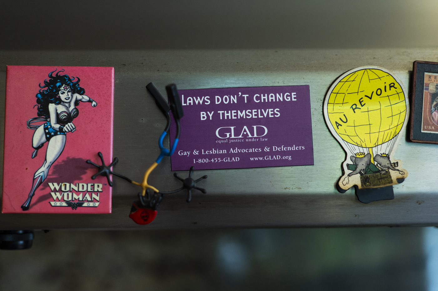business card for Gay & Lesbian Advocates and Defenders (GLAD) that says "Laws Don't hange By Themselves" besides other miscellaneous stickers and magnets