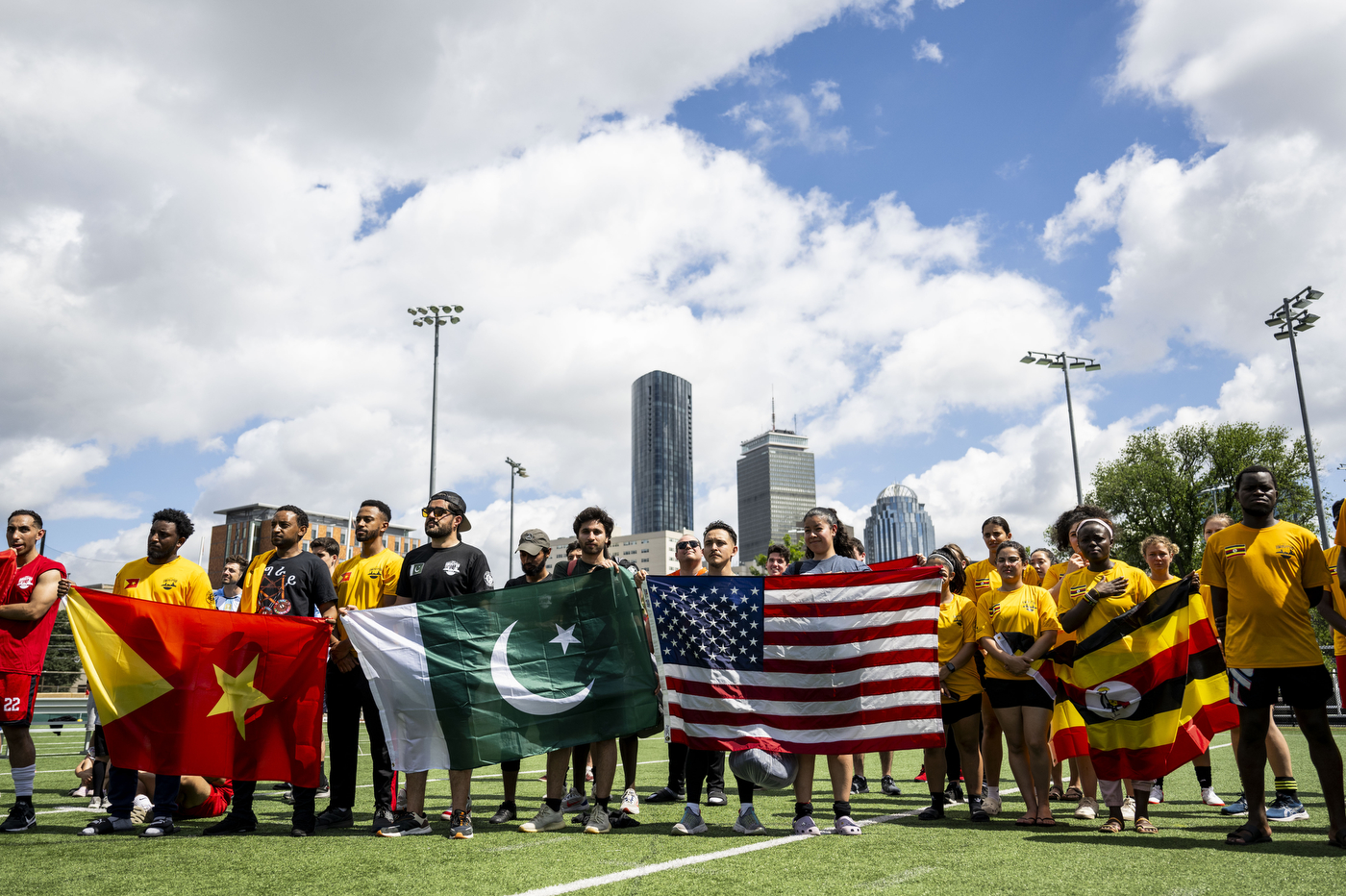 People stand in line on a soccer field holding flags.