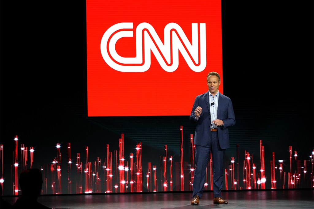 Chris Licht standing in front of CNN logo