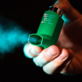 person using an inhaler to expel air