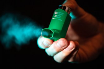 person using an inhaler to expel air