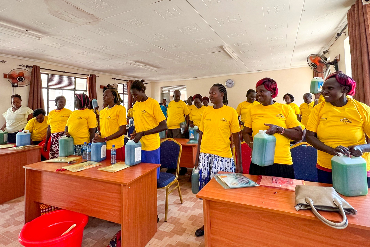 Multiple people wear yellow shirts and stand together in a classroom.