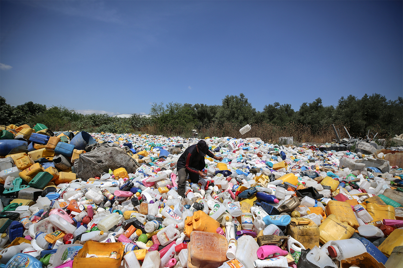 worker standing in a large field of plastic waste