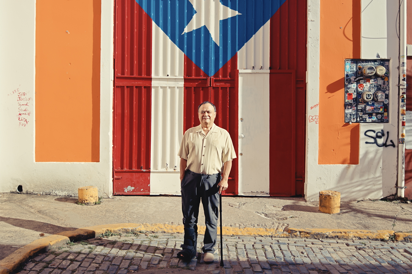A person stands in front of the flag of Puerto Rico.