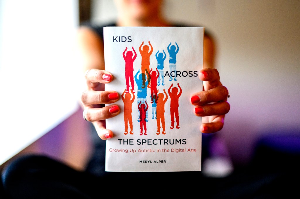 person holding Meryl Alper's new book Kids Across The Spectrums