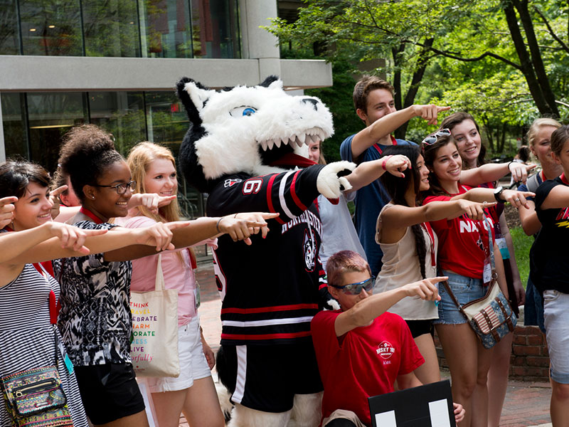 king husky mascot with students on campus