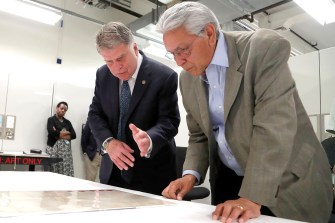David Ferriero and Kevin Gover inspecting a document on a table.