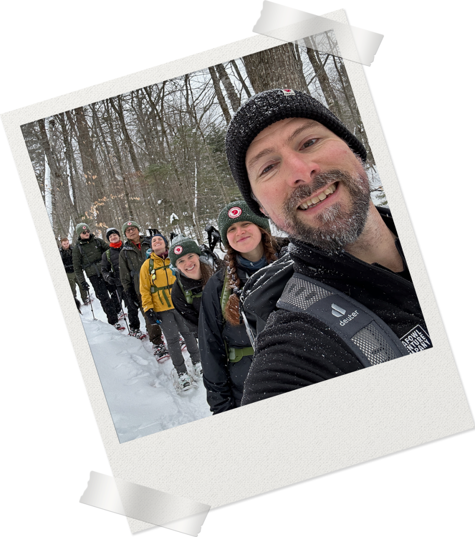 Decorative Polaroid frame containing a selfie of David Fatula with a line of hikers behind him smiling at the camera in a snowy forest.