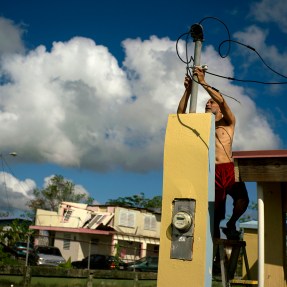 A resident of Puerto Rico tries to connect electrical lines.