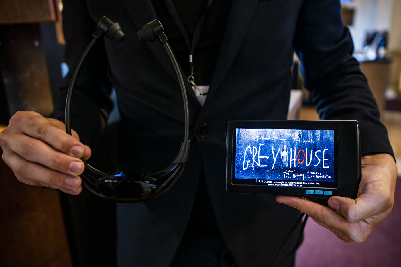 hand held closed-captioning device displaying Grey House