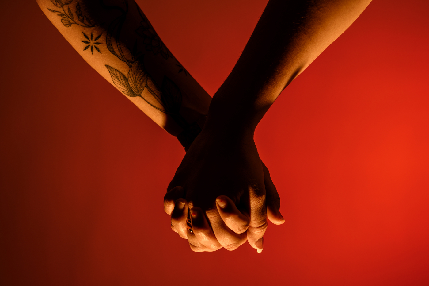two people holding hands on a red background