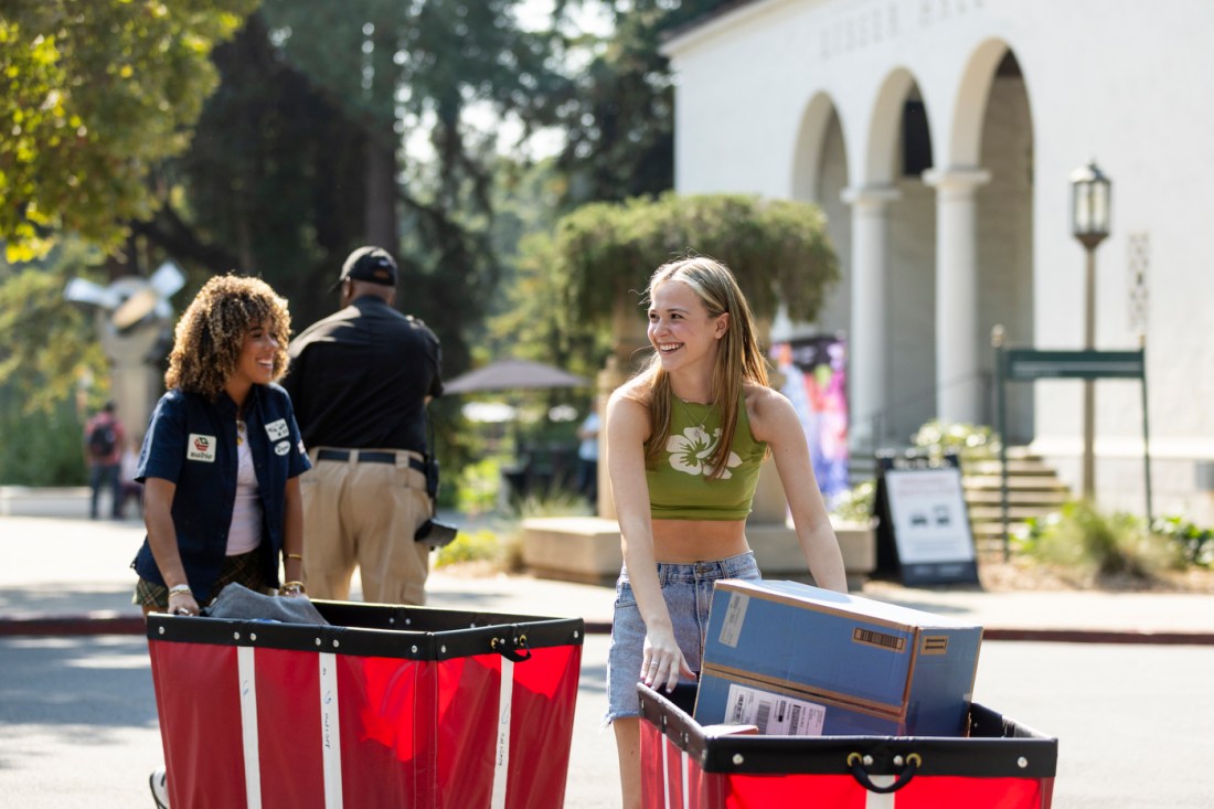 Sydney Deriggs and Clara Hawks pushing move-in bins on Mills College campus.