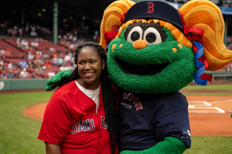 Brittany posing for a photo on the field with Tessie, a green monster